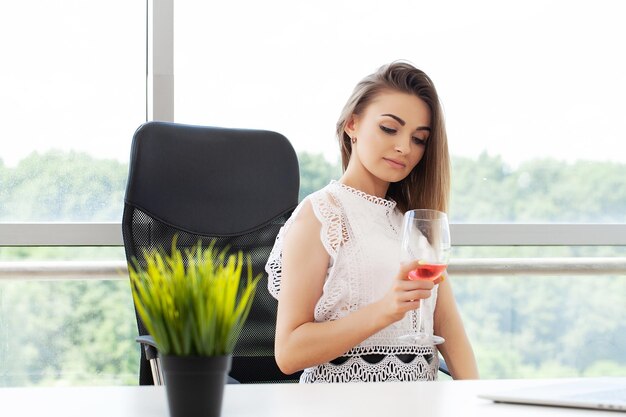 Szczęśliwa biznesowa kobieta opiekająca kieliszek wina w biurze