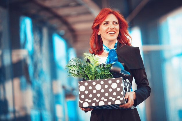 Szczęśliwa bizneswoman świętuje sukces w dzielnicy biurowej z pudełkiem pełnym jej rzeczy osobistych z biura tuż po tym, jak rzuciła pracę.