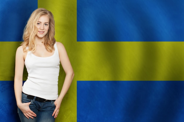 Szczęśliwa blondynka studentka z tłem flagi Szwecji Podróżuj i ucz się języka Szwecji