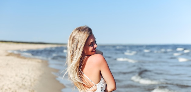 Szczęśliwa blondynka w wolnym szczęściu na plaży oceanu stojąca prosto i pozująca