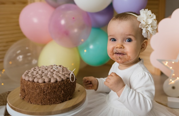 Szczęśliwa brudna dziewczynka zjada ciasto i patrzy w kamerę