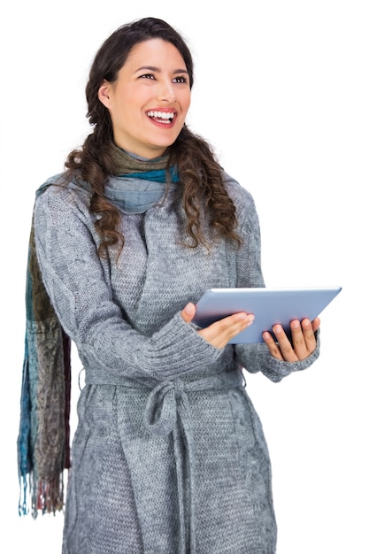 Szczęśliwa brunetka jest ubranym zimy odzieżowego mienia jej pastylkę