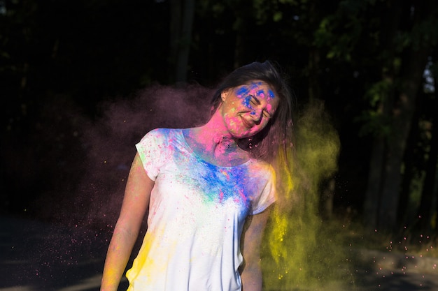 Szczęśliwa brunetka kobieta pozuje z eksplodującym proszkiem Holi w parku