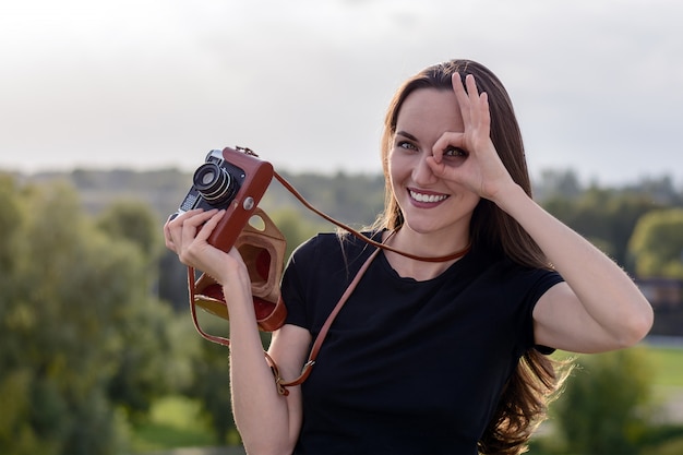 Szczęśliwa brunetki kobieta robi fotografii z retro kamerą na miasto ulicie
