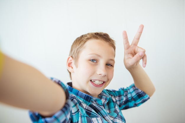 Szczęśliwa chłopiec robi selfie i pokazuje kciuk up