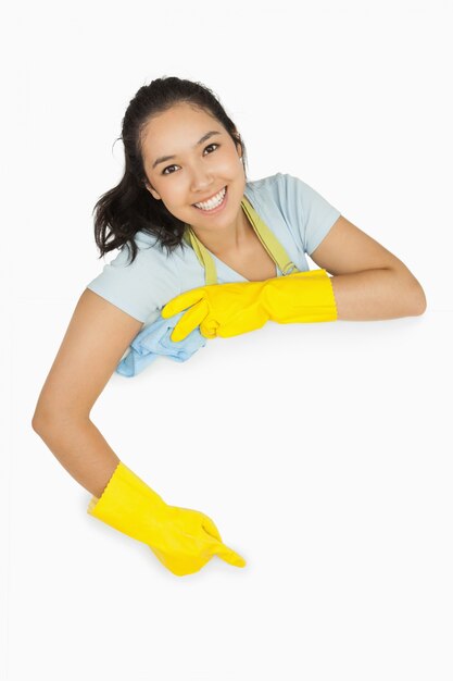Szczęśliwa cleaning dama wskazuje biel powierzchnia
