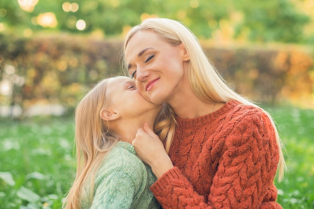 Szczęśliwa córka całuje matkę w parku jesień.