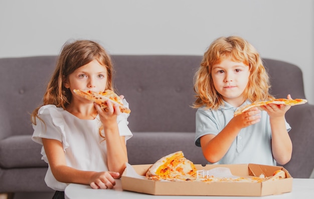Szczęśliwa córka i syn jedzą pizzę dzieci bawią się razem przy obiedzie w domu l