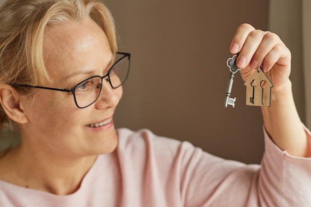 Szczęśliwa dojrzała kobieta trzymająca klucze do mieszkania Koncepcja hipoteki na parapetówkę