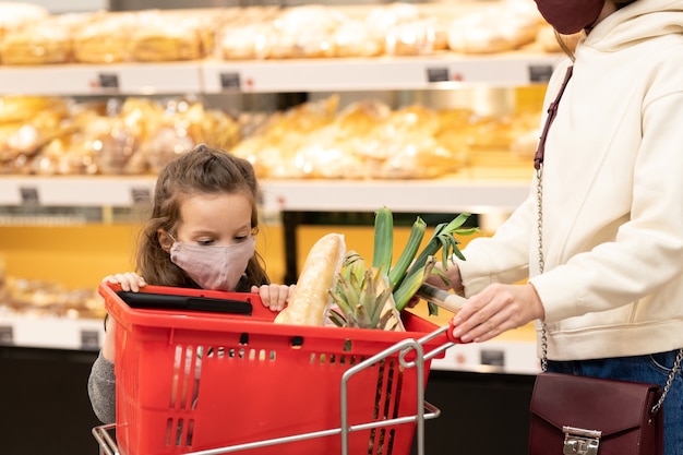 Szczęśliwa dojrzała para patrzy na sprzedawcę przy kasie w supermarkecie, kupując owoce i płacąc kartą kredytową