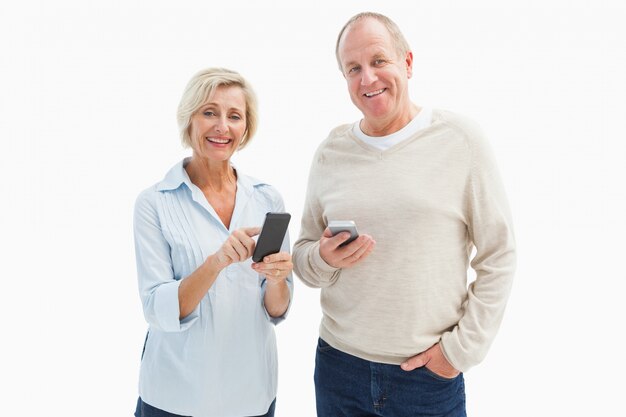 Szczęśliwa dojrzała para używa ich smartphones