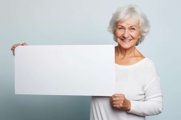 Szczęśliwa dojrzała starsza kobieta trzymająca pusty biały baner z izolowanym portretem studyjnym