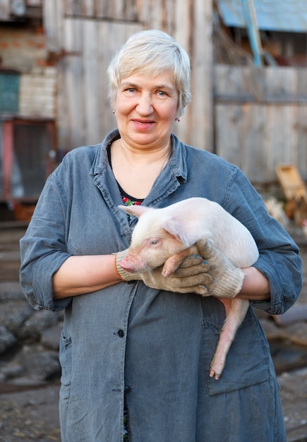 Szczęśliwa dorosła kobieta trzyma małą świnię