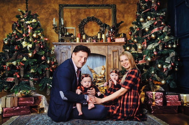 Szczęśliwa duża rodzina z dziećmi w noworocznym wnętrzu domu przy kominku przy choince