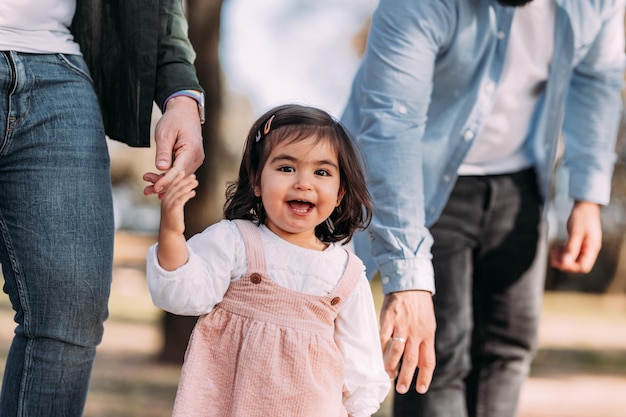 Szczęśliwa dziewczyna ciesząca się z rodziną ręka w rękę z koncepcją tatusia dwóch ojców