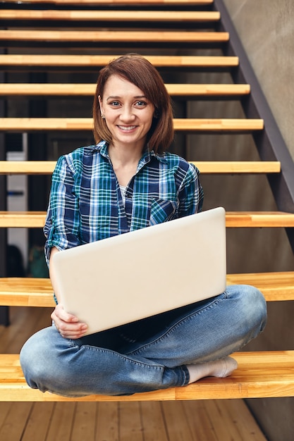 Zdjęcie szczęśliwa dziewczyna freelancer pracuje na laptopie w domu leśniczego