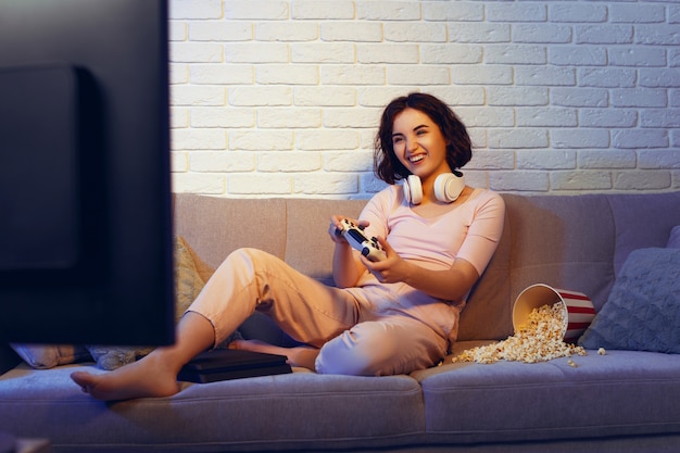Zdjęcie szczęśliwa dziewczyna gracza bawi się grając w gry wideo na konsoli w ciemnym pokoju