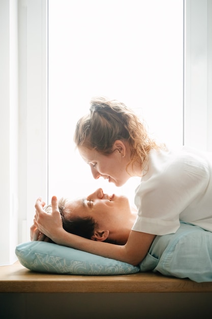 Szczęśliwa dziewczyna i mężczyzna przytulanie w pobliżu okna w domu. Białe i niebieskie ubrania. Walentynki.