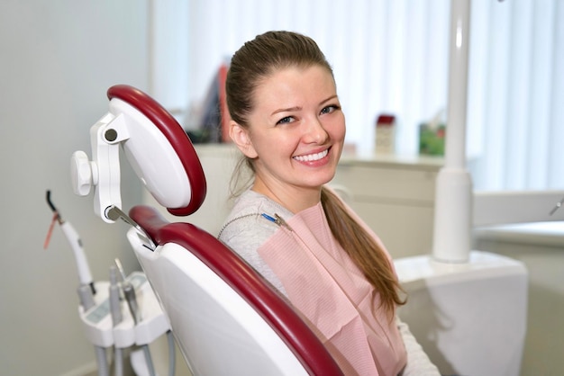Szczęśliwa dziewczyna młoda zadowolona uśmiechnięta kobieta pacjentka z idealnym białym uśmiechem na krześle medycznym
