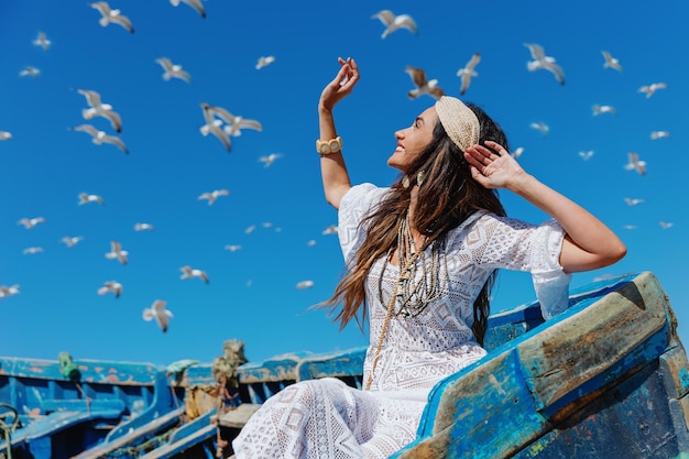 Szczęśliwa dziewczyna patrzy na niebo i latające mewy. Essaouira. Maroko