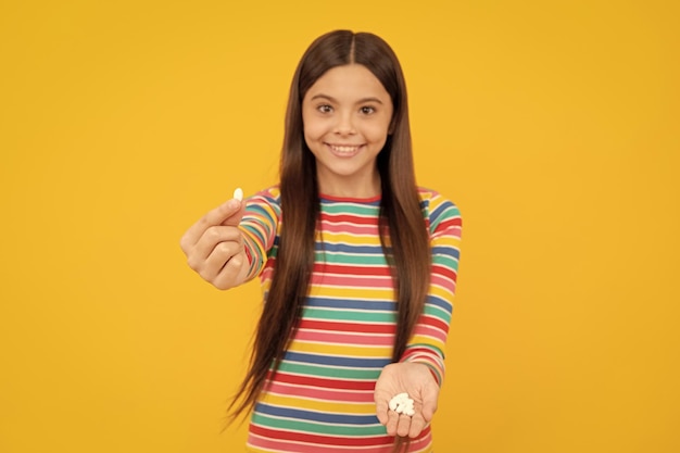 Szczęśliwa dziewczyna pokazując naturalne dodatki do żywności lub witaminy pigułki witamina
