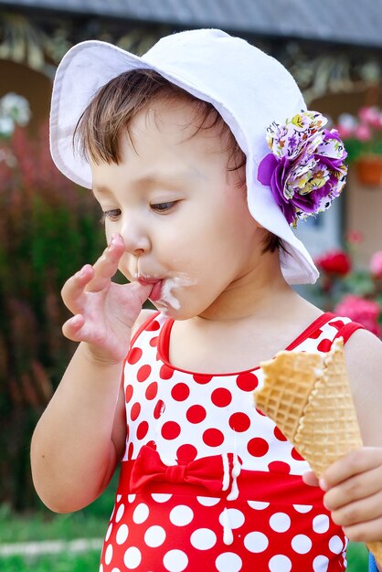 Zdjęcie szczęśliwa dziewczyna przedszkolna jedząca kolorowe lody w waflowym stożku w słoneczny letni dzień