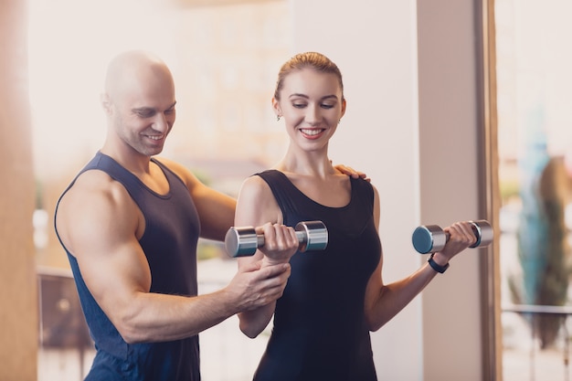 Szczęśliwa dziewczyna robi siły ćwiczenia dumbbell rękach