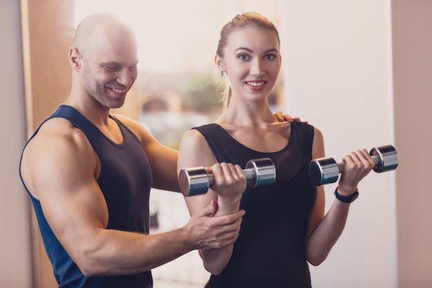 Szczęśliwa dziewczyna robi siły ćwiczenia dumbbell rękach