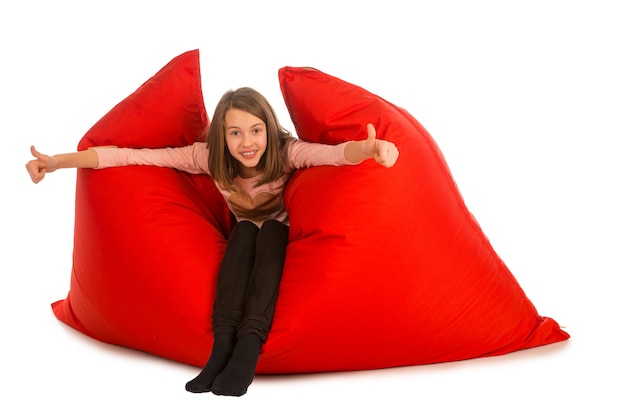 Zdjęcie szczęśliwa dziewczyna siedzi na czerwonej kanapie worek fasoli do salonu lub innego pokoju na białym tle