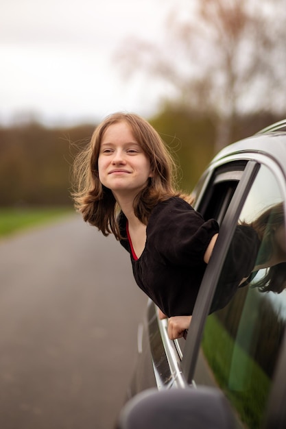 Szczęśliwa dziewczyna wygląda przez okno samochodu w letni dzień