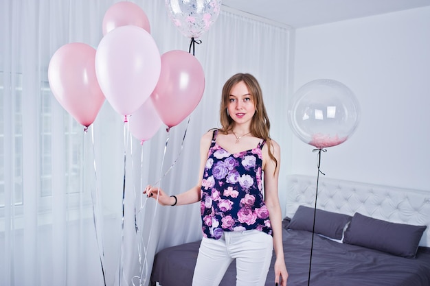 Szczęśliwa dziewczyna z kolorowymi balonami na łóżku w pokoju Świętowanie tematu urodzin