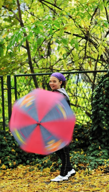 szczęśliwa dziewczyna z parasolem na świeżym powietrzu w parku w jesienny dzień deszczu