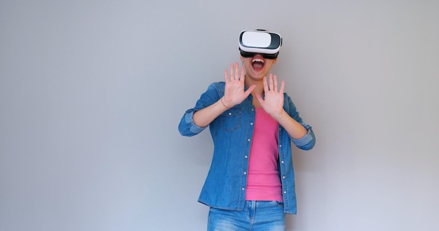 Szczęśliwa dziewczyna zdobywająca doświadczenie w używaniu okularów VR z zestawem słuchawkowym wirtualnej rzeczywistości, odizolowana na białym tle
