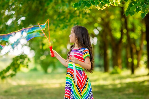 Szczęśliwa dziewczynka brunetka bawi się baniek mydlanych w parku