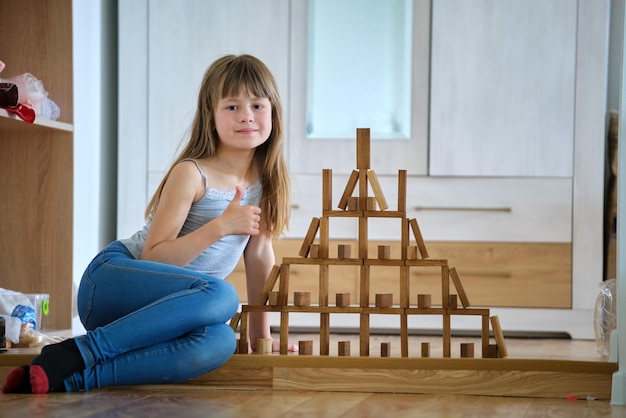 Szczęśliwa dziewczynka gra w układanie drewnianych klocków zabawek w strukturę o wysokim stosie Kontrola ruchu dłoni i budowanie koncepcji umiejętności obliczeniowych