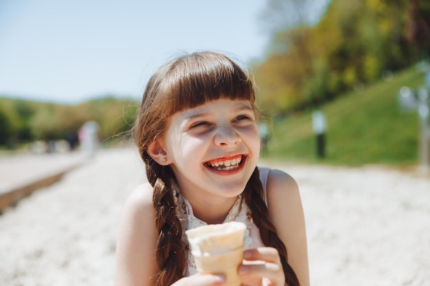 Szczęśliwa dziewczynka jedzenie lodów na plaży w letnie wakacje