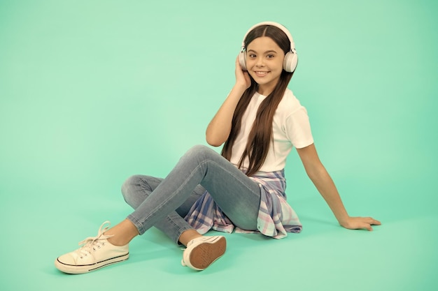 Szczęśliwa dziewczynka słucha muzyki w nowoczesnych słuchawkach bezprzewodowych