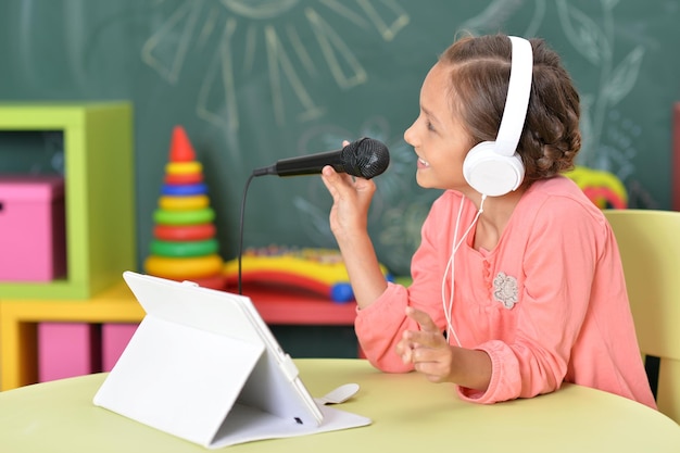 Szczęśliwa dziewczynka śpiewa karaoke w domu.