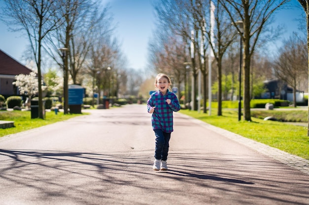 Szczęśliwa dziewczynka uśmiechnięta mała dziewczynka biegająca o zachodzie słońca ładna dziewczynka biegająca na placu zabaw ogród Szczęśliwa rodzinna dziewczynka