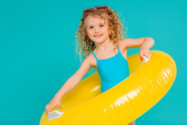 Szczęśliwa dziewczynka w swimsuit z okręgiem odizolowywającym na błękitnym tle