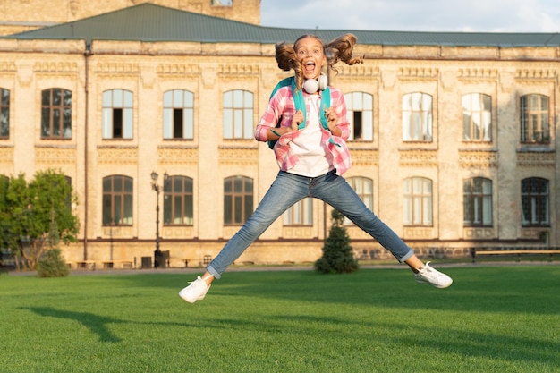 Szczęśliwa energiczna nastolatka skacząca na szkolnym boisku na zewnątrz Dzień wiedzy