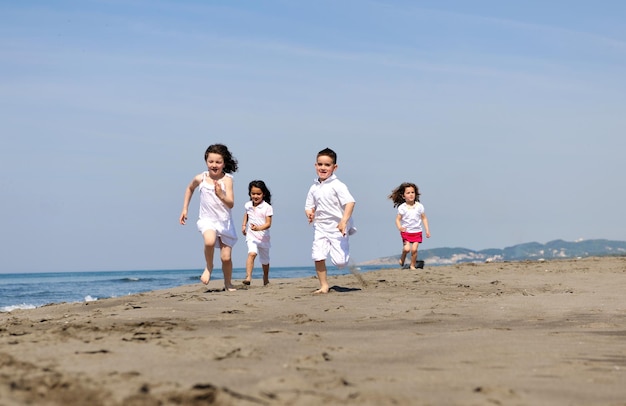 szczęśliwa grupa młodych ludzi baw się biega i skacze na plaży piękna piaszczysta plaża