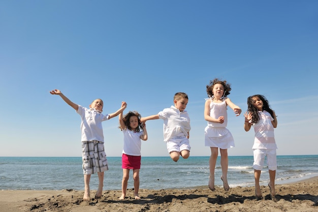 szczęśliwa grupa młodych ludzi baw się biega i skacze na plaży piękna piaszczysta plaża