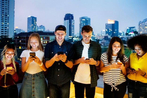 Szczęśliwa Grupa Młodzi Dorosli Używa Smartphones W Pejzażu Miejskim
