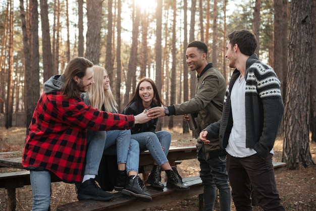 Szczęśliwa grupa przyjaciele siedzi outdoors w lesie.