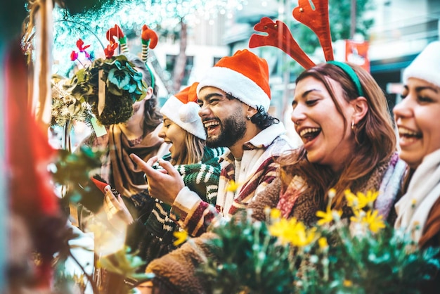 Szczęśliwa grupa przyjaciół bawiących się w sklepie z pamiątkami na rynku bożonarodzeniowym
