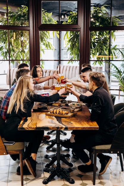 Szczęśliwa grupa przyjaciół pijących i brzęczących piwem i koktajlami w barze browarniczym w restauracji Koncepcja stylu życia napojów z chłopakami i dziewczynami bawiącymi się razem