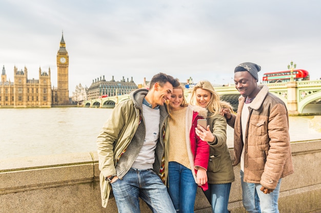Szczęśliwa grupa przyjaciół wielorasowych za pomocą smartfona w Londynie
