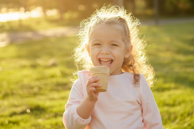 Szczęśliwa i mała dziewczynka je lody w letnim parku