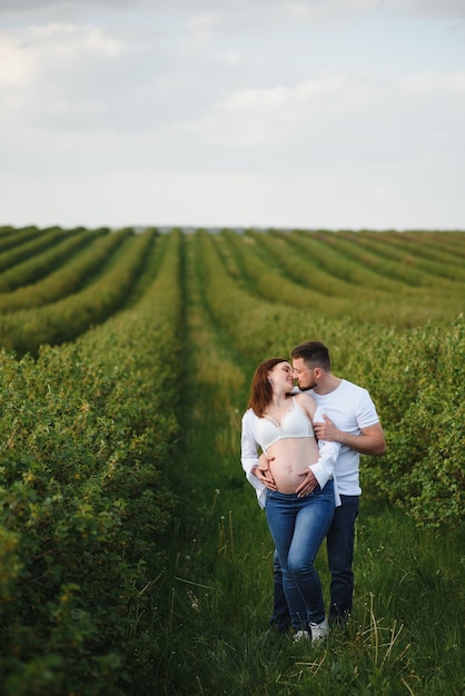 Szczęśliwa i młoda ciężarna para ściska w naturze